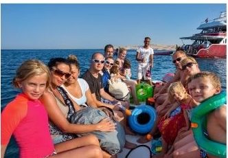 Családok és gyerekek a hajó fedélzetén, háttérben a búvárhajó